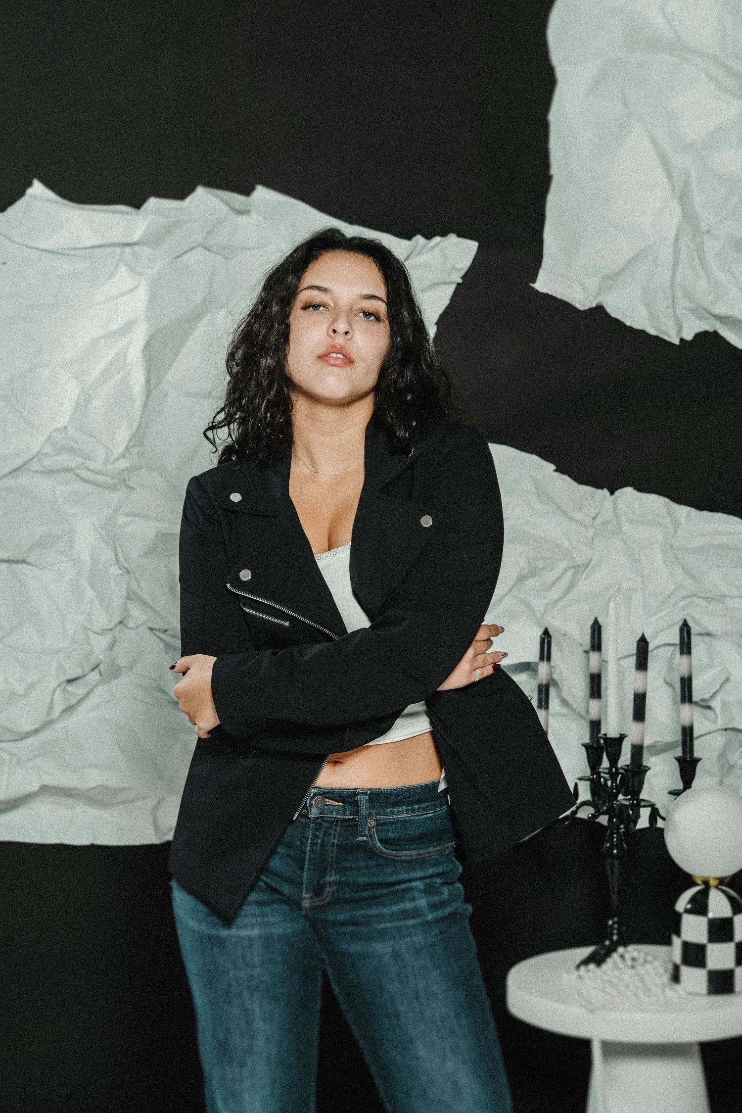 A dynamic fashion photoshoot features a model in a black leather jacket and jeans posing against a black and white backdrop.
