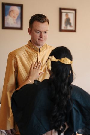 A person in a gold shirt plays with a black dog in a sequence of four similar photos.