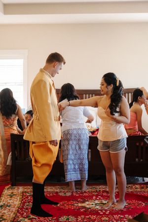 Participants learn ballroom dance steps on a red carpeted floor in a bright indoor studio.