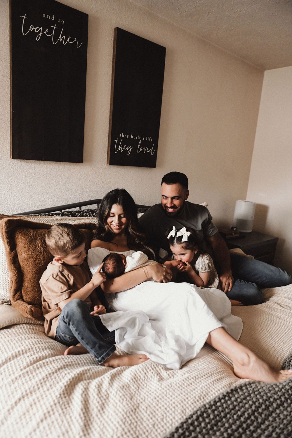 A family relaxes together on a comfortable couch with decorative wall signs visible above.