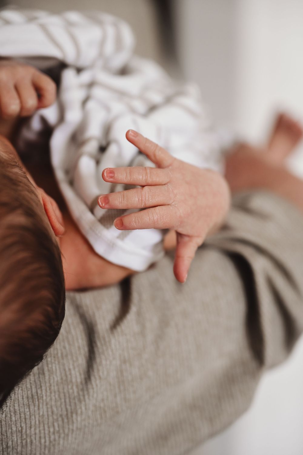 Close-up sequence of gentle hands holding and caressing on a soft gray surface.