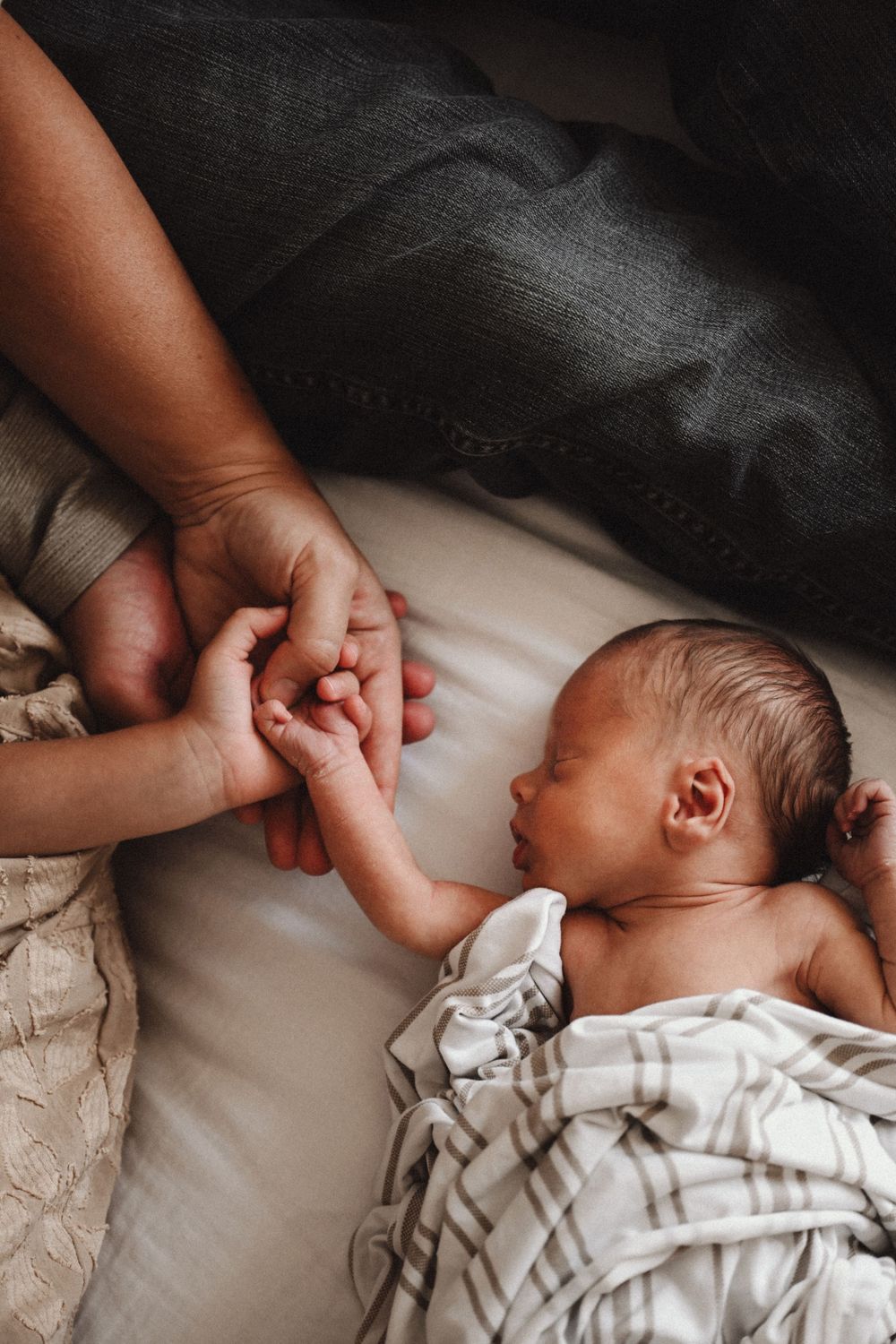 Intimate series showing tender moments with a newborn baby in white clothing.