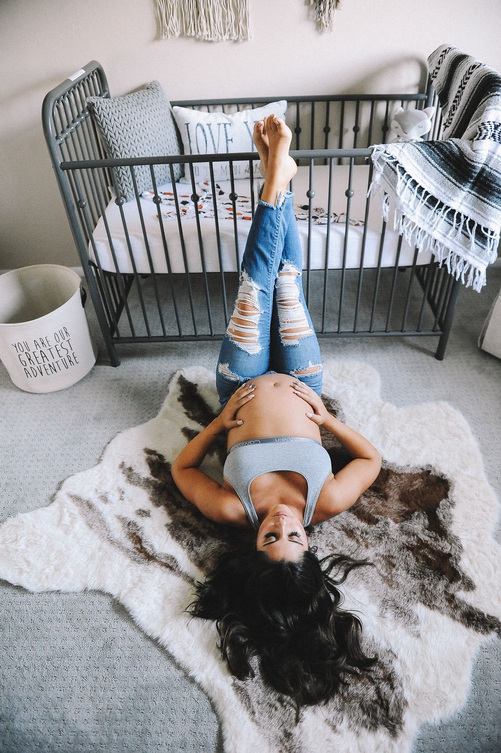 Artistic sequence of a person lying on a plush rug near a dark metal crib.
