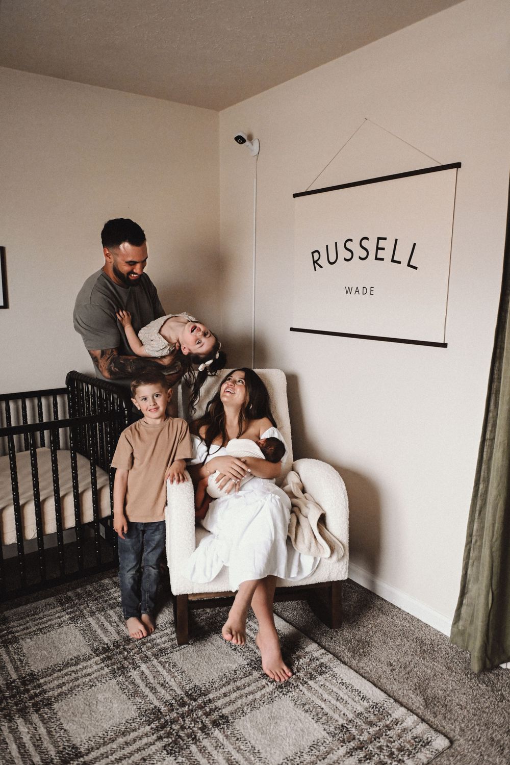 Family lifestyle photos taken in a nursery with modern minimalist wall decor.