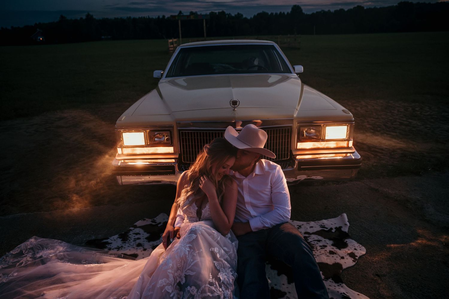 A romantic date scene is set up at sunset with a truck bed lined with blankets and string lights.