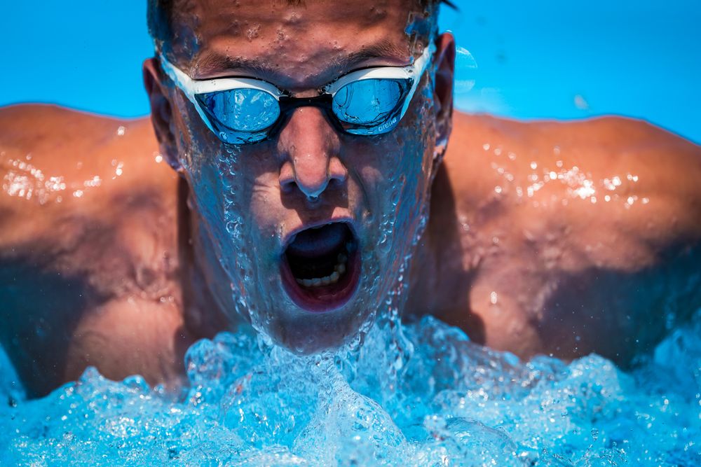 A competitive swimmer performs butterfly stroke in a pool showing a sequence of movement in bright blue water.