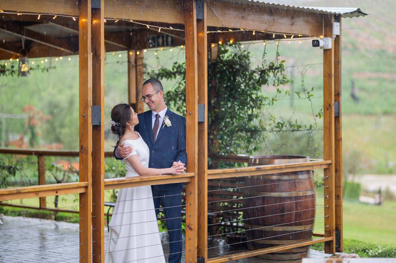 Couples share intimate moments during outdoor photo shoots at a rustic covered wooden porch overlooking scenic landscape.