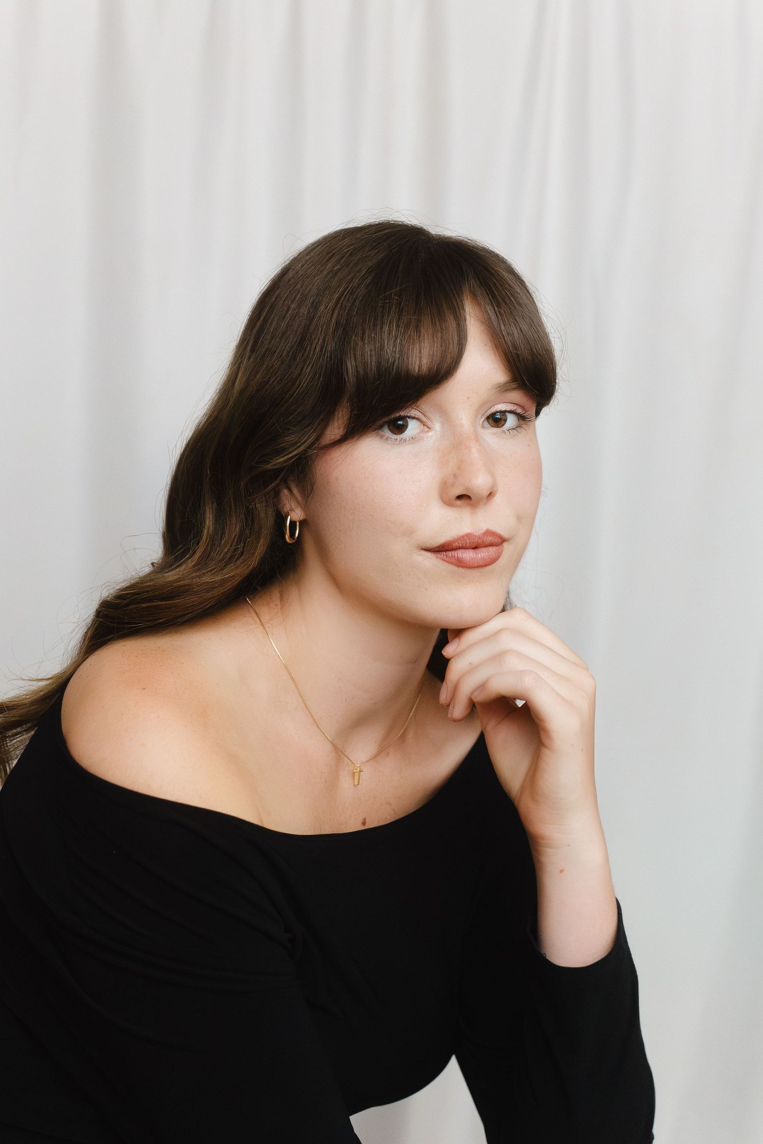 Studio portrait sequence against white backdrop showing contemplative poses in black attire.