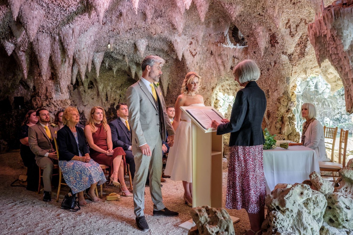 Wedding ceremony guests stand together at a traditional pink-decorated celebration.