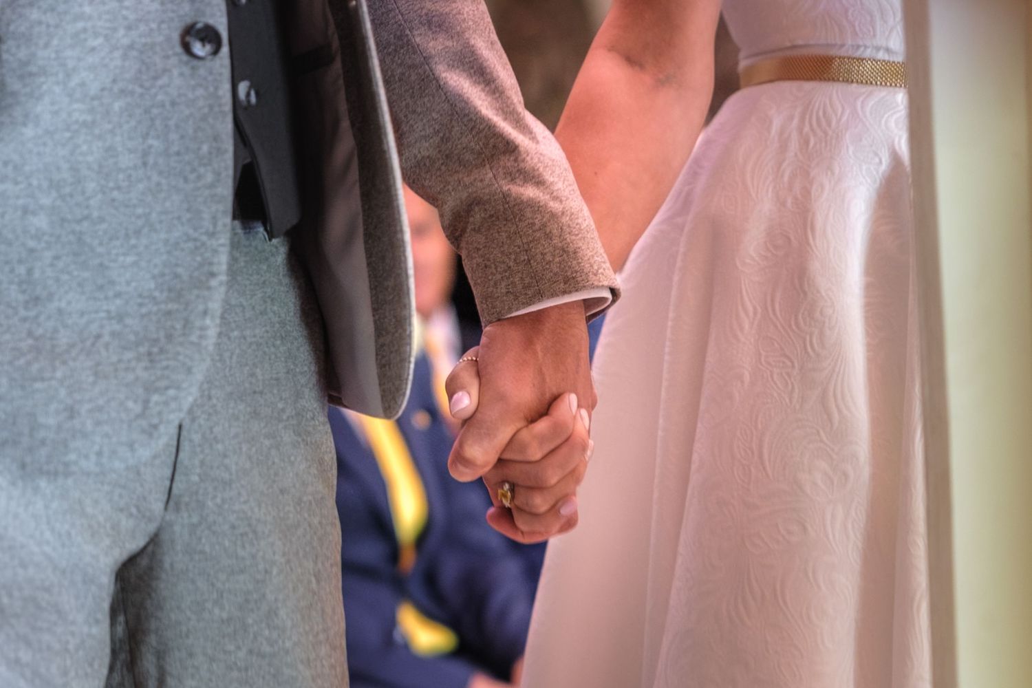 A couple holding hands in wedding attire, showcasing an intimate moment during their ceremony.