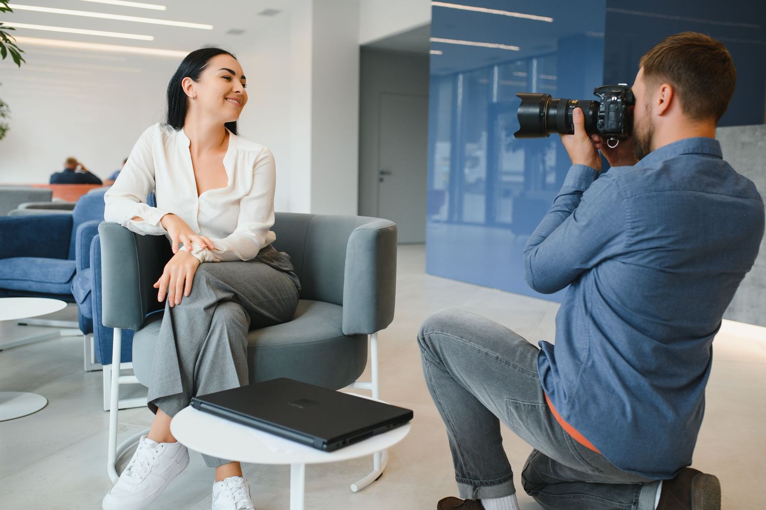 Business colleagues in a modern office engage in an animated conversation while sitting on a gray couch.