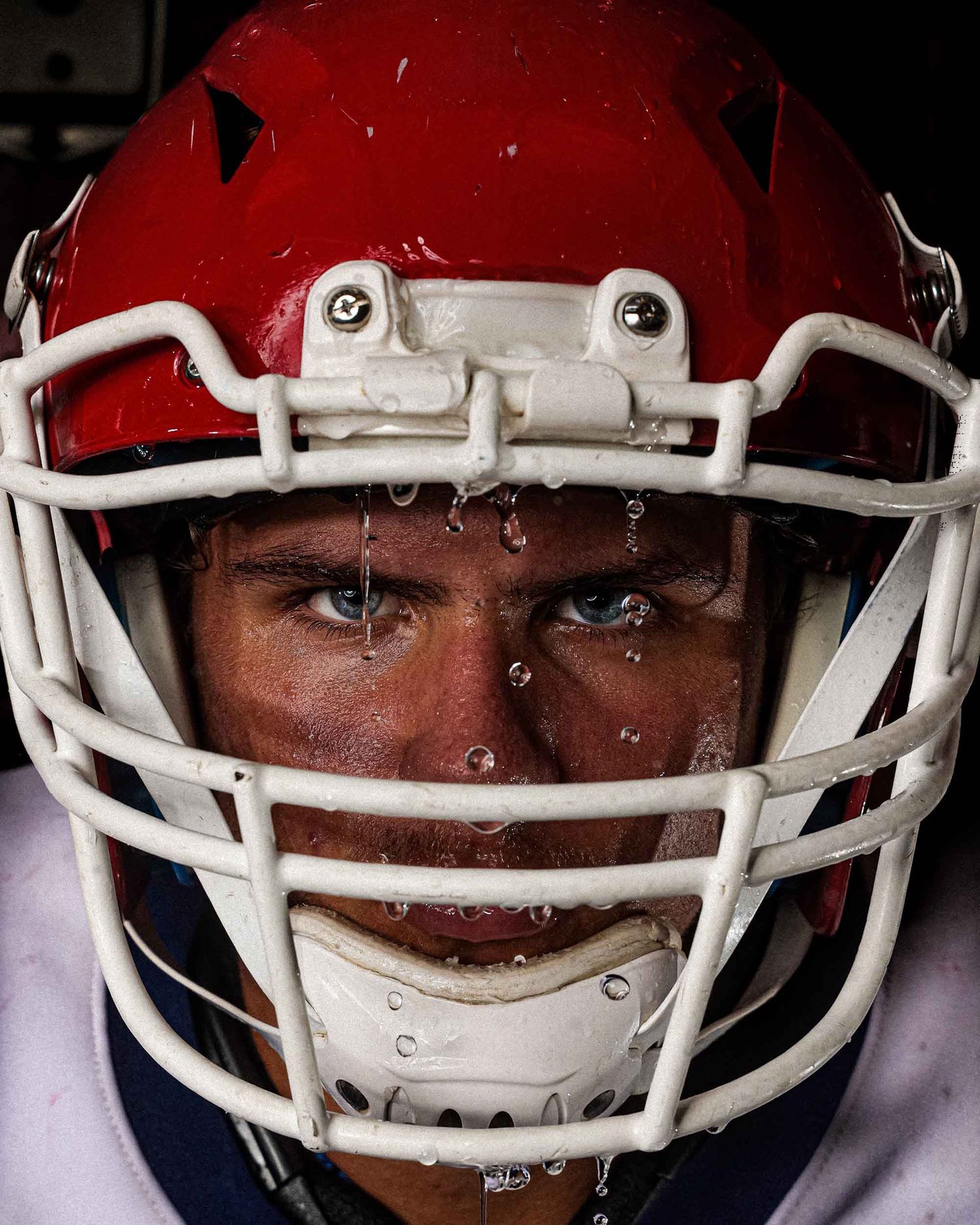 A series of intense football player close-up headshots aligned horizontally showing focused eyes beneath red helmets.