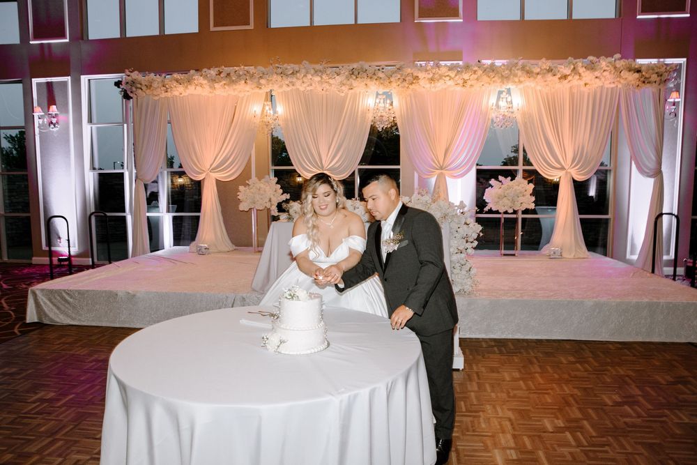 Elegant wedding reception venue with white draping, crystal chandeliers and romantic lighting creating a dreamy atmosphere.