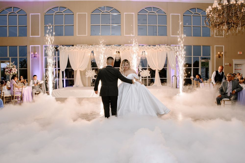 A grand wedding celebration with elegant decorations shows guests mingling in a luxurious ballroom with arched windows.