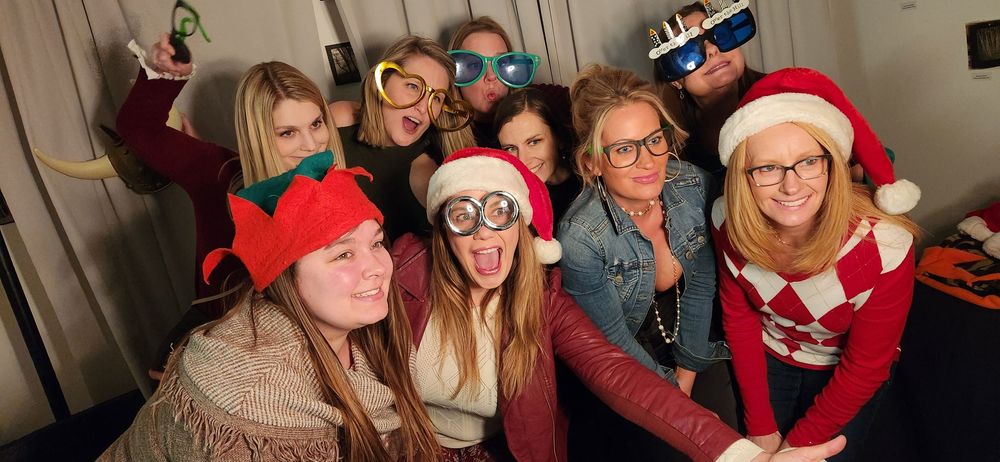 A group enjoying holiday festivities and making silly poses together while wearing festive winter attire.