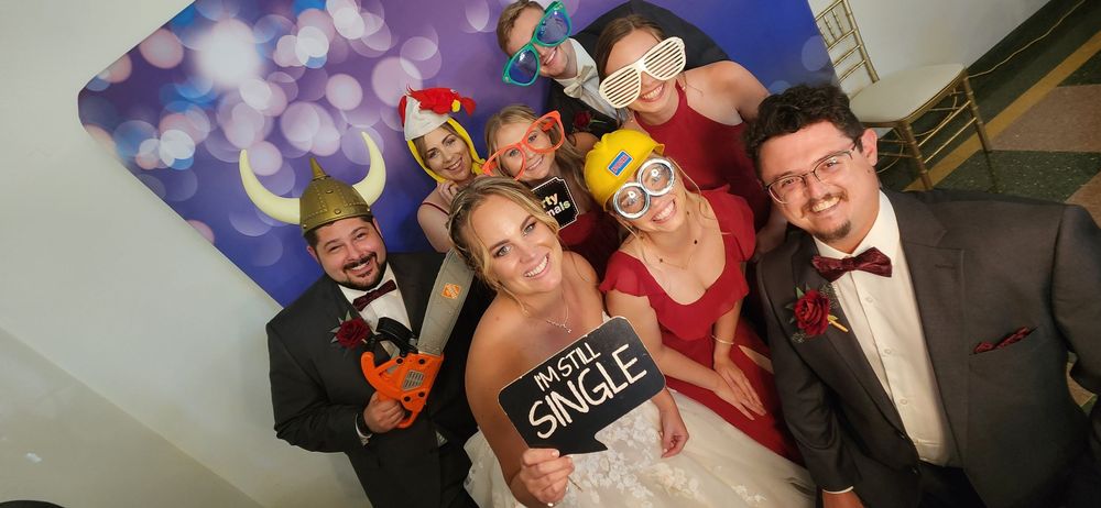 A fun photo booth montage showing five frames of wedding guests posing and celebrating with props in each shot.