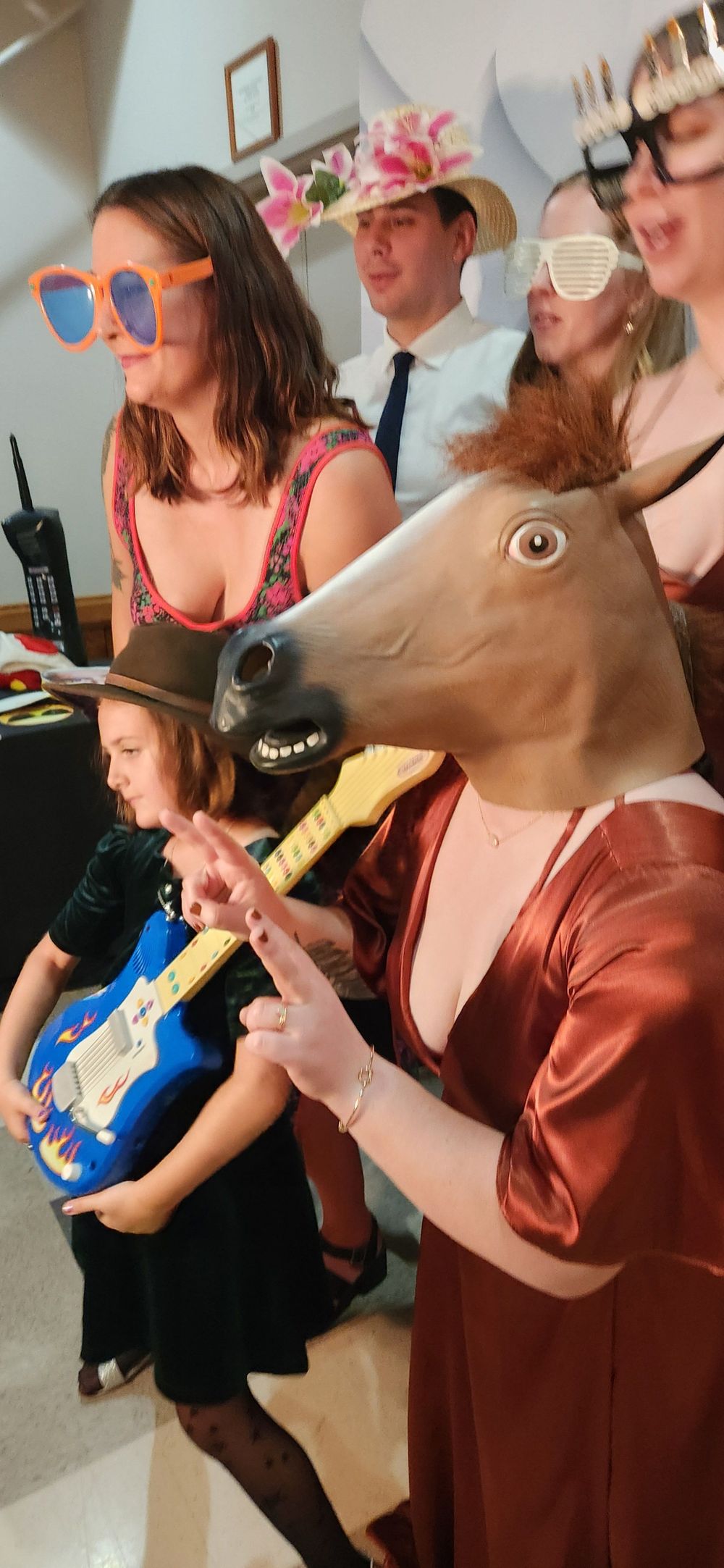 Group of friends at a party playing air guitar and having fun indoors while wearing informal attire.