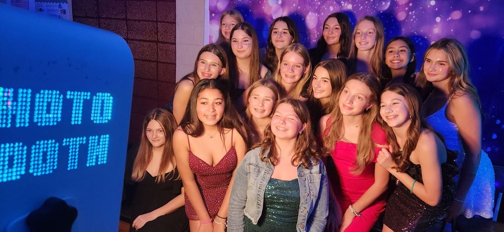 Groups of young friends enjoying a night out posing together at a nightclub under blue and purple lighting effects.
