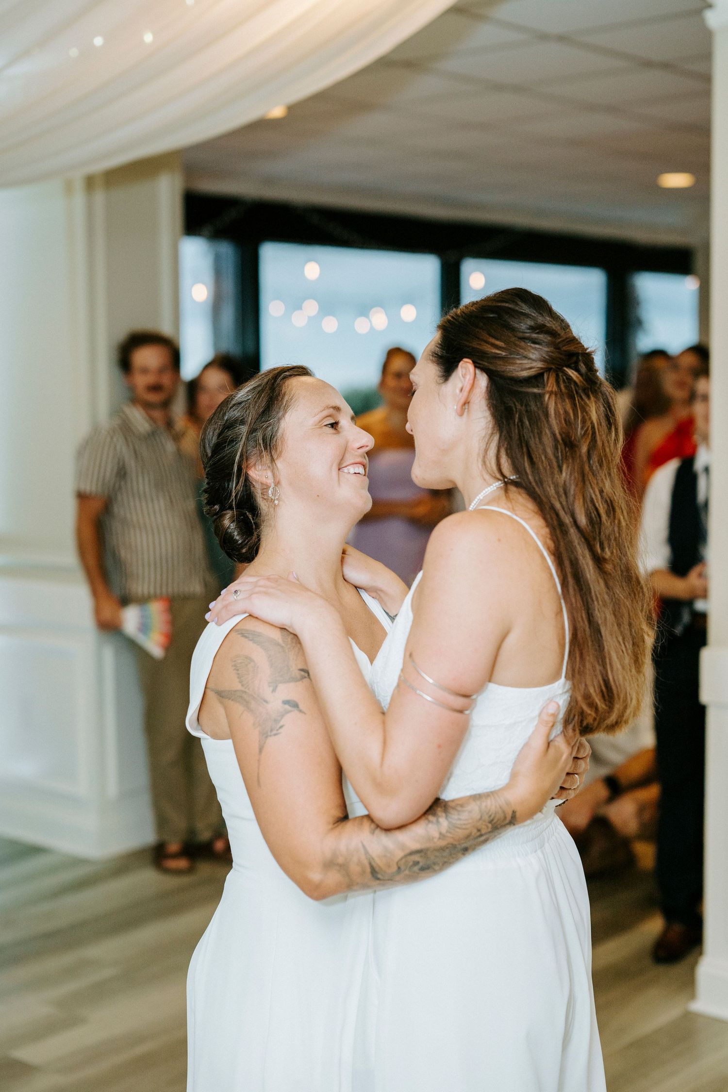 Two happy people in white dresses share an intimate dance moment at their wedding reception.