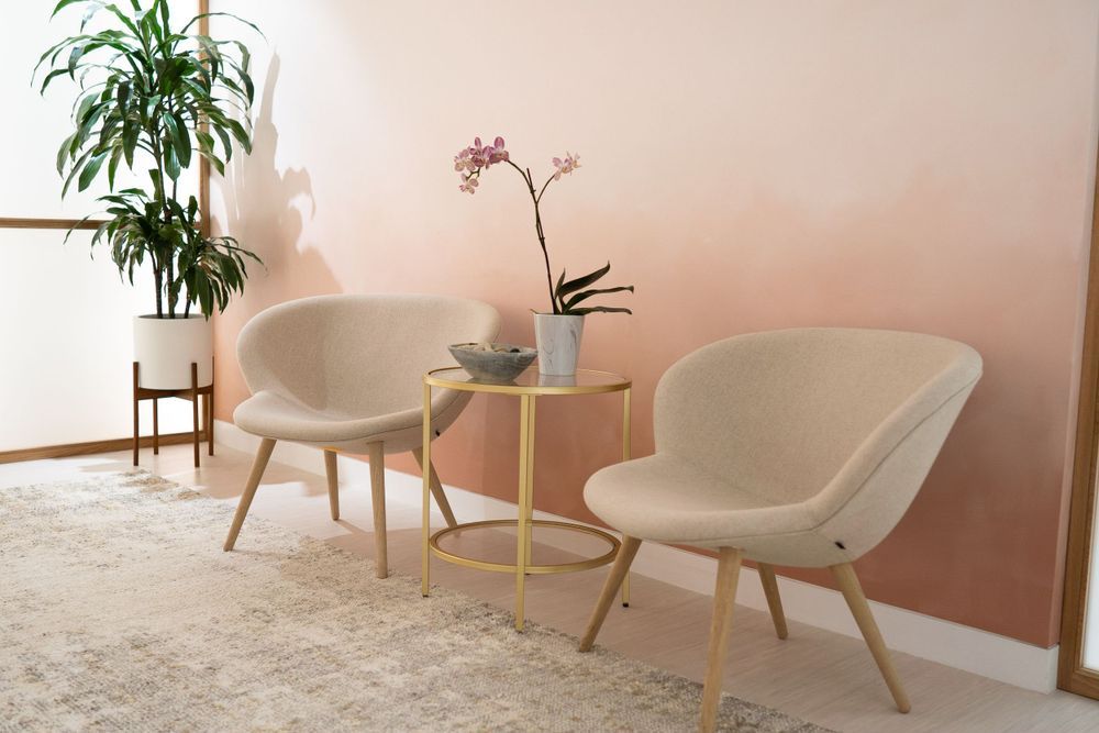 Sleek modern interior with pink walls, houseplants, and white accent chairs.
