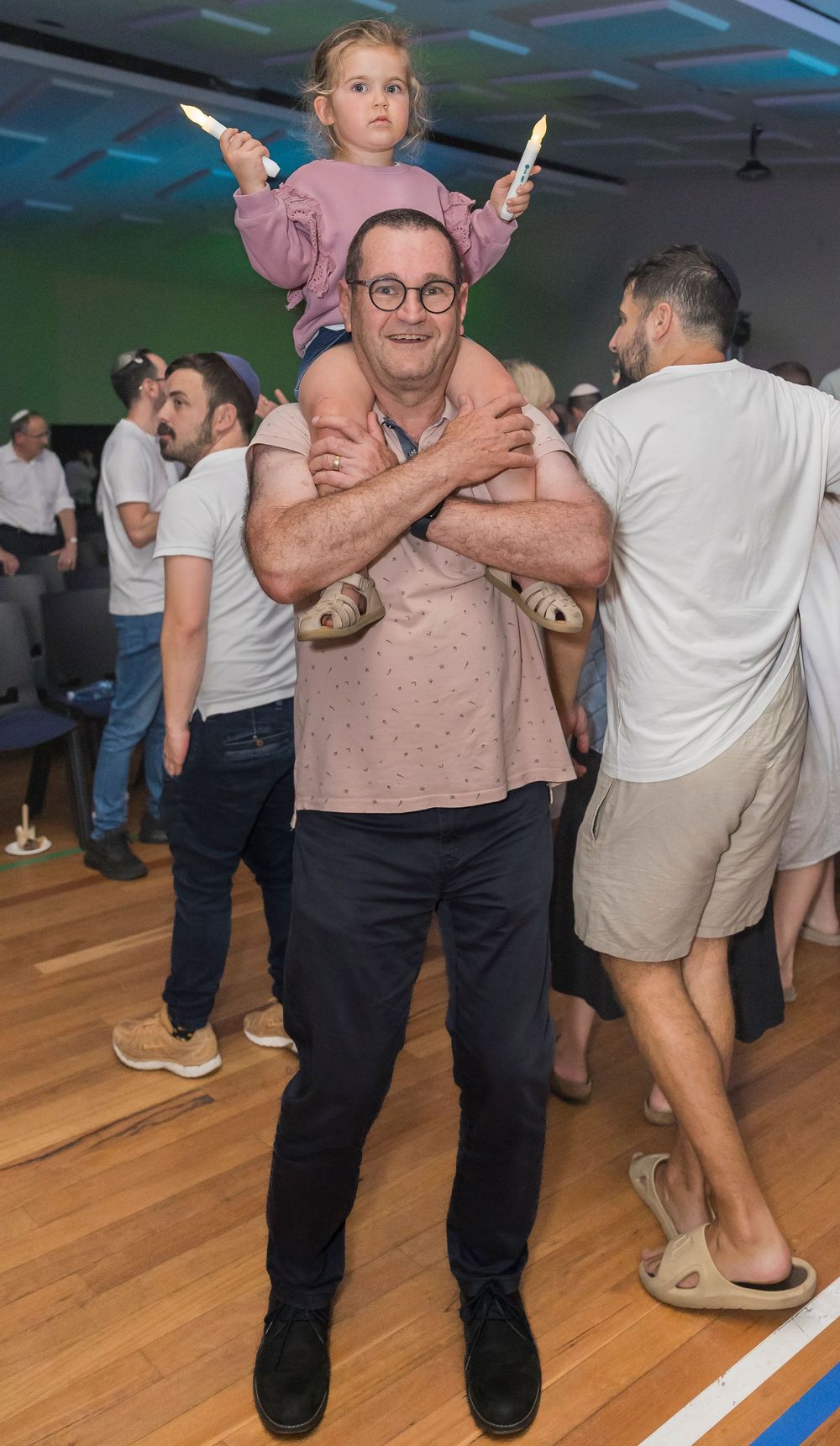 People dancing together on a wooden dance floor at an indoor social gathering or party event.