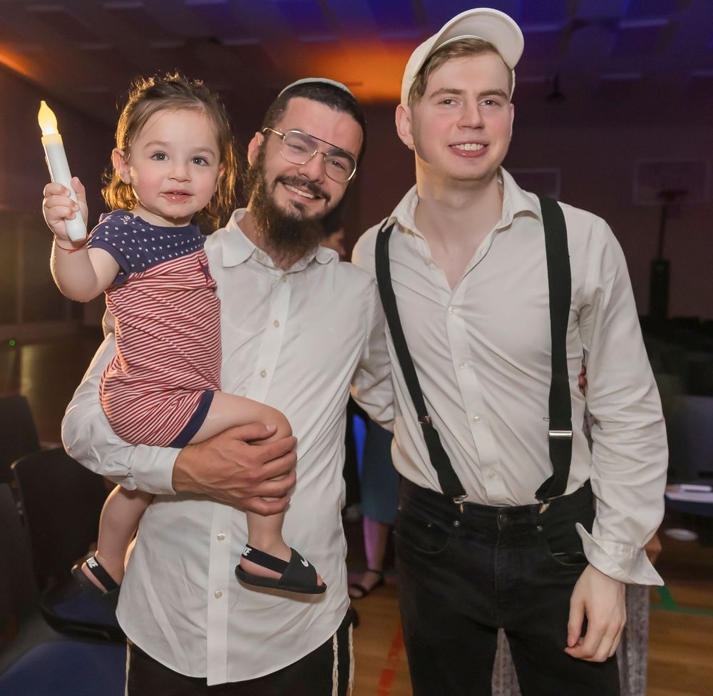 People dancing and celebrating at a wedding reception in formal attire with white shirts and suspenders.