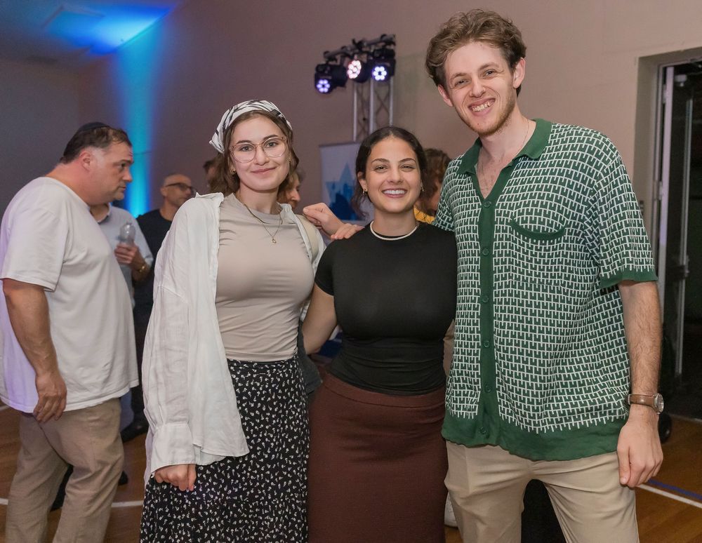 People dancing and socializing at a party with blue lighting in the background.