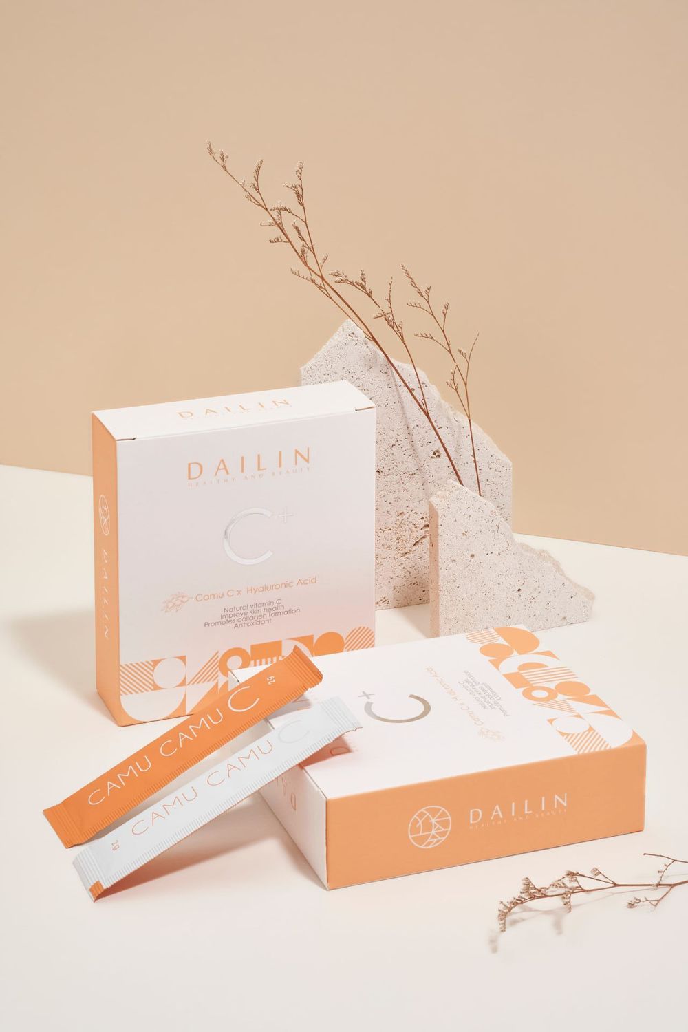 Clean white skincare product boxes arranged with delicate twigs on a beige surface with orange accents.