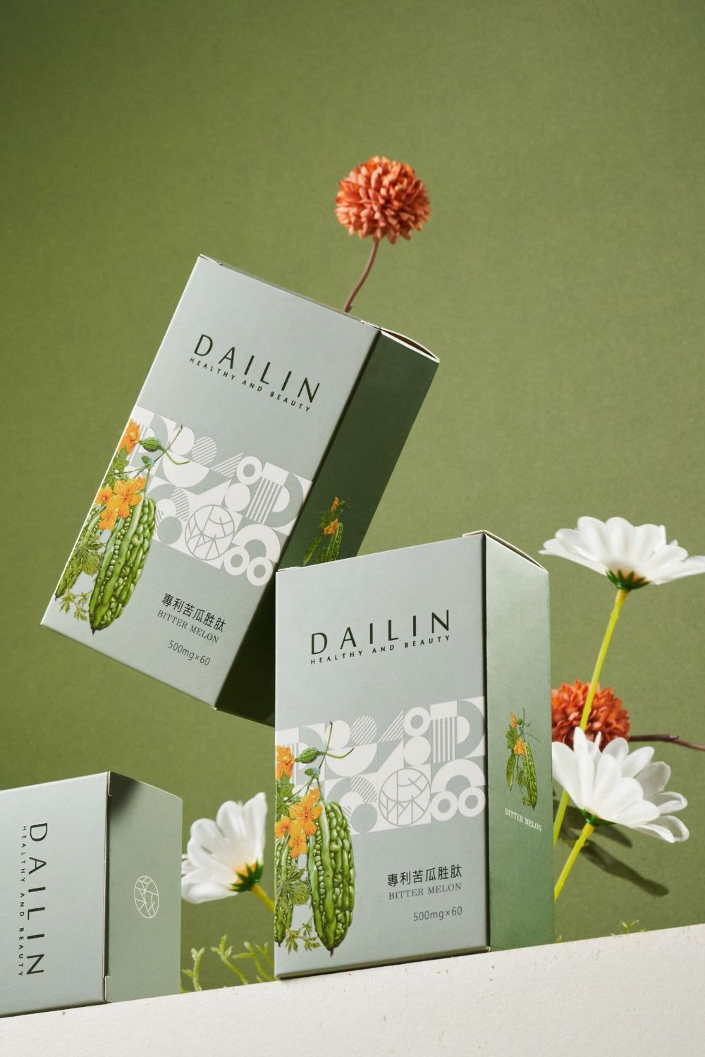 Elegant green product boxes for Dailin skincare with floral decorative elements and fresh flowers against sage background.
