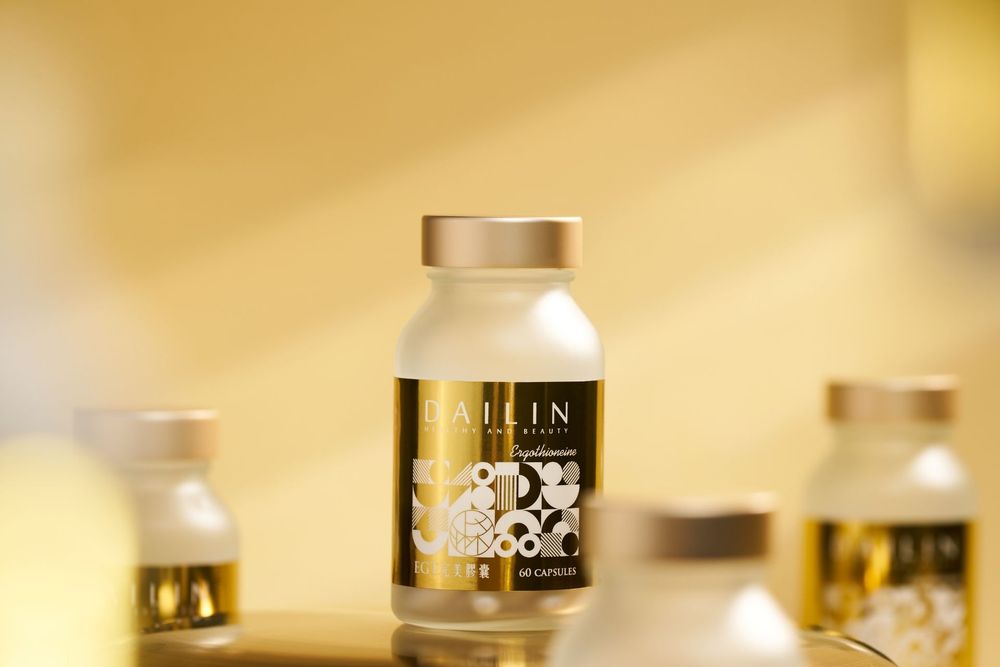 A glass supplement bottle with gold cap and label sits against a warm blurred background with similar bottles visible.