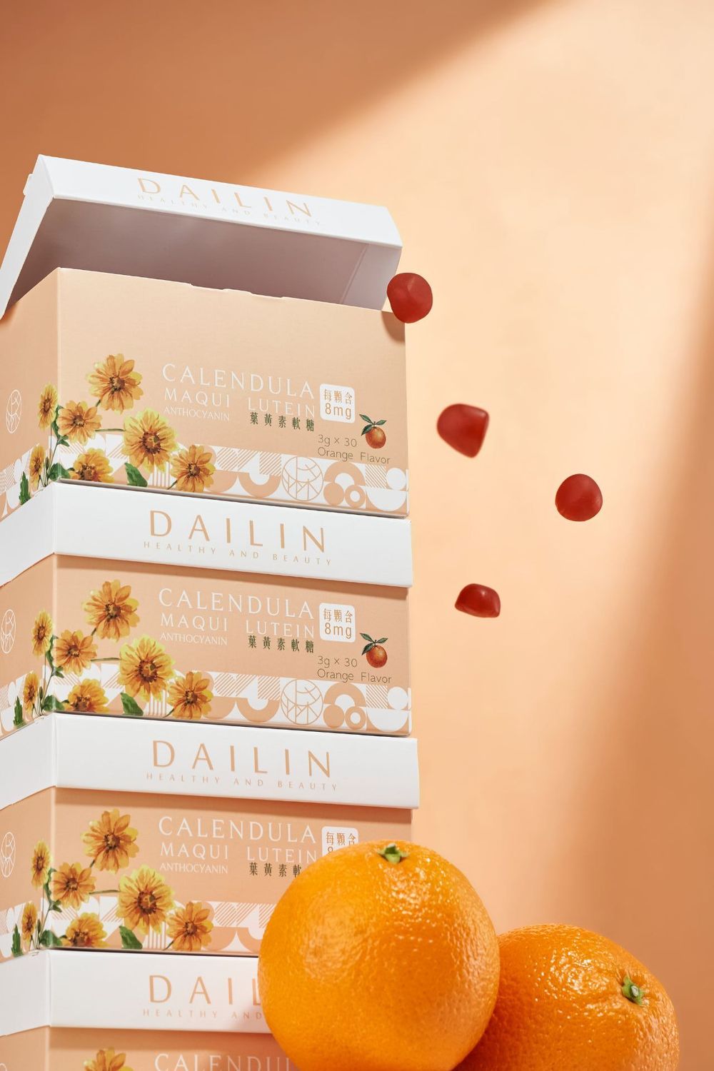 White skincare product boxes with floral designs are arranged with fresh oranges against a peachy background.