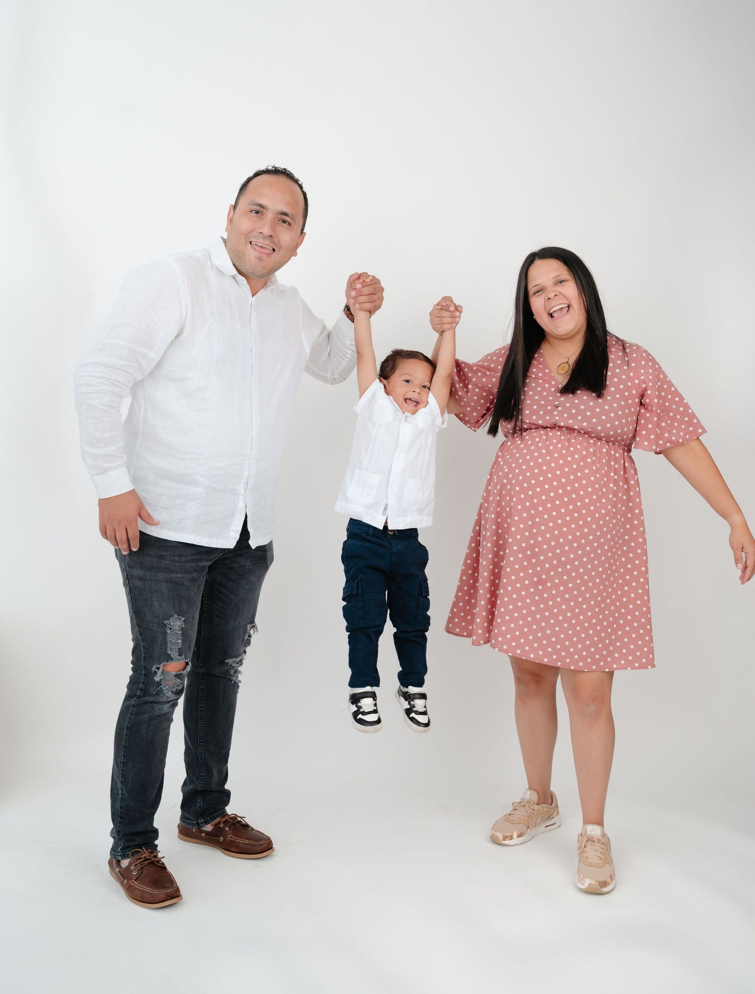 Family members in coordinated white and pink outfits pose playfully against a white studio backdrop in a series of shots.