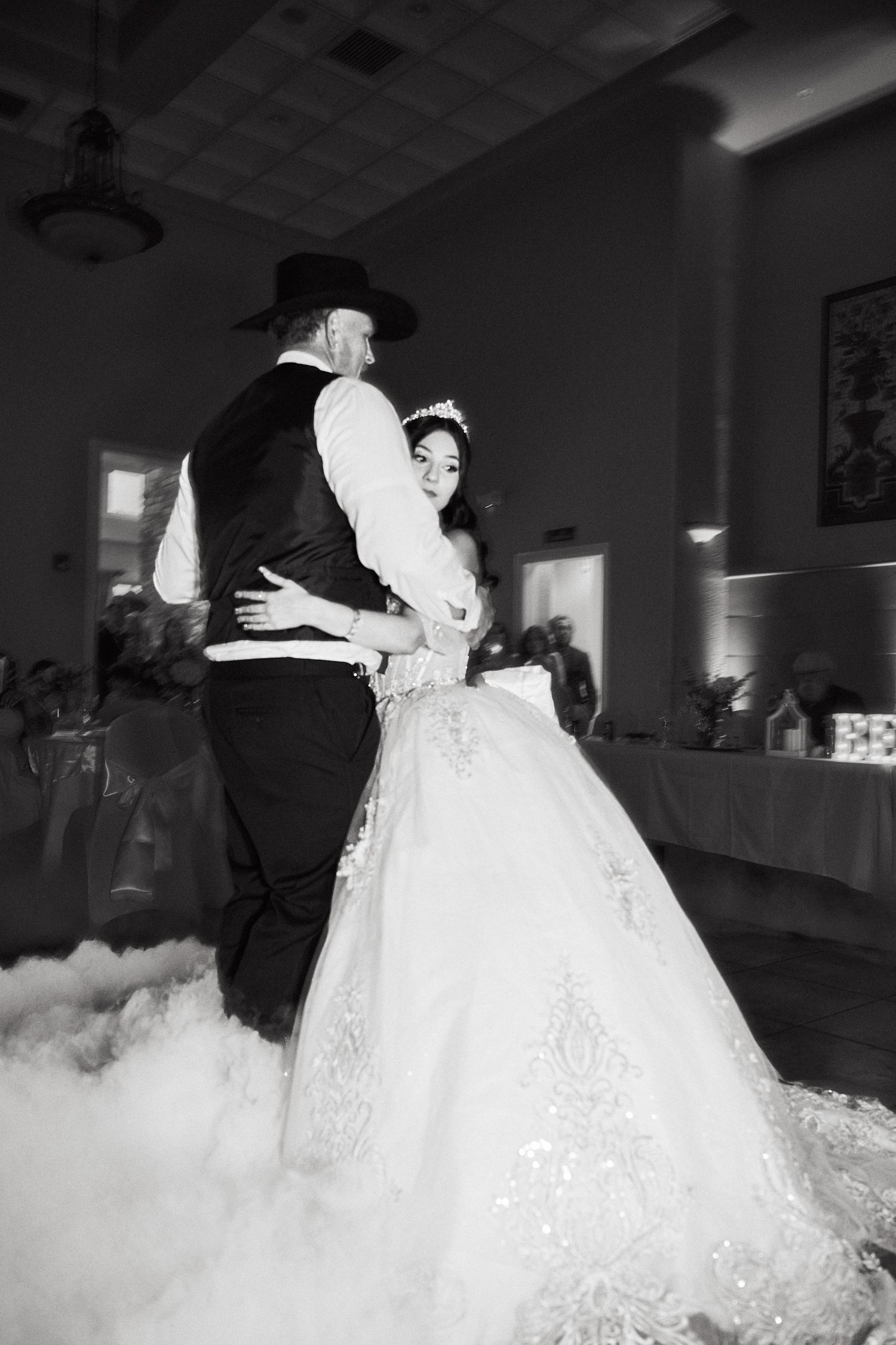 A couple shares their first dance at a wedding reception with fog effects on the dance floor.