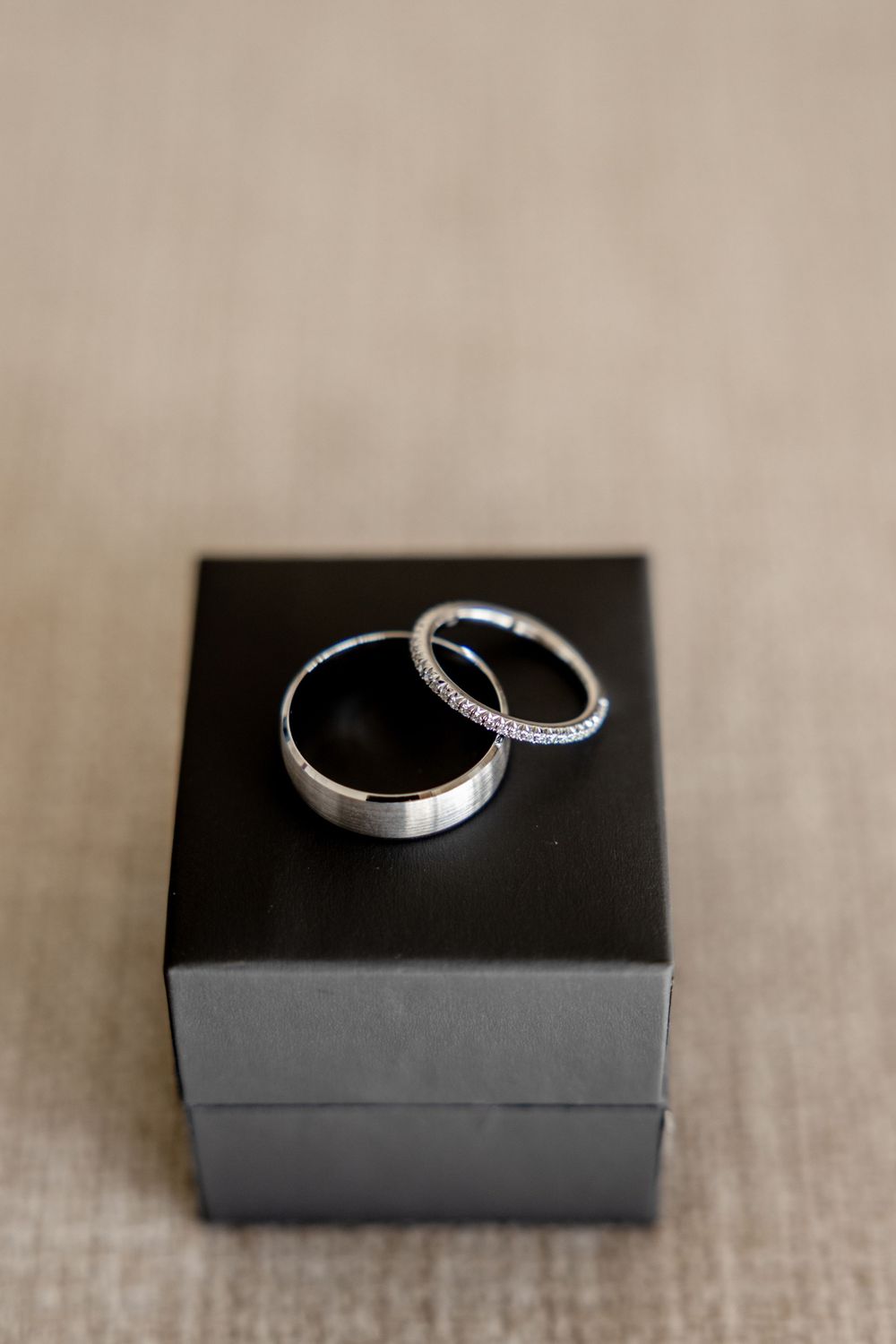 Two silver wedding bands, one diamond eternity ring, displayed on a black jewelry box.
