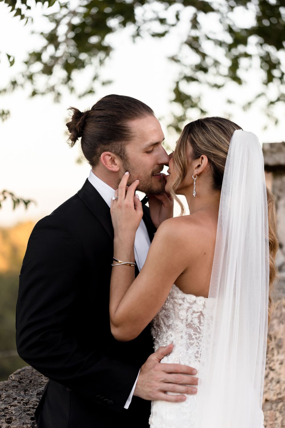 A romantic wedding couple sharing intimate kisses in a series of black and white portraits outdoors.