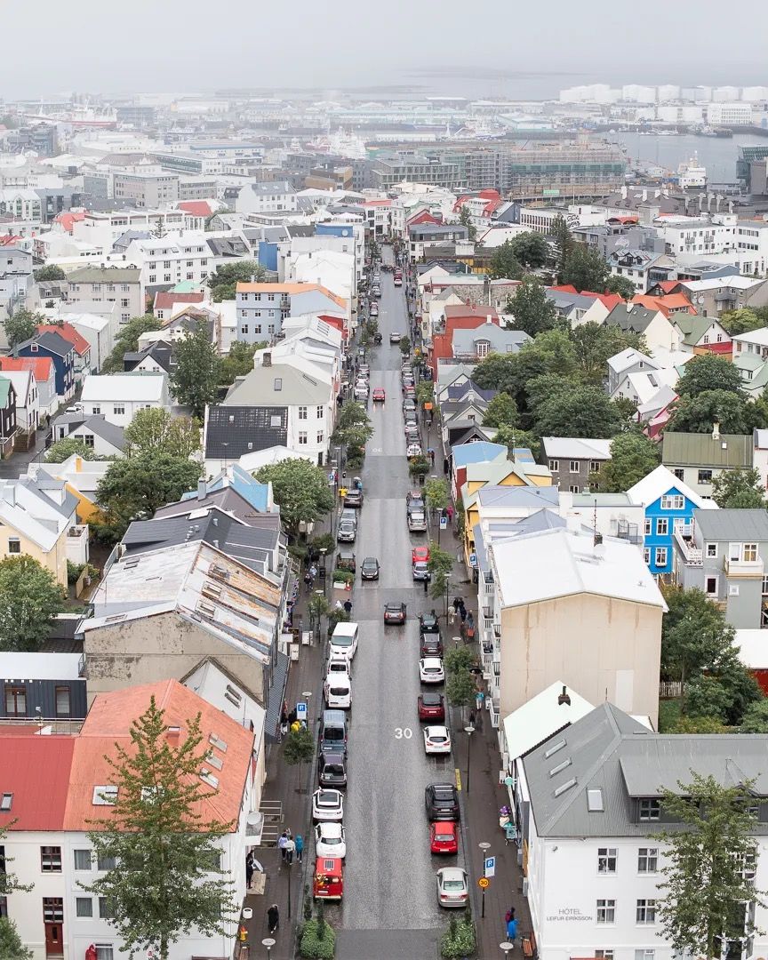 Aerial view of a long city street lined with colourful buildings and cars.