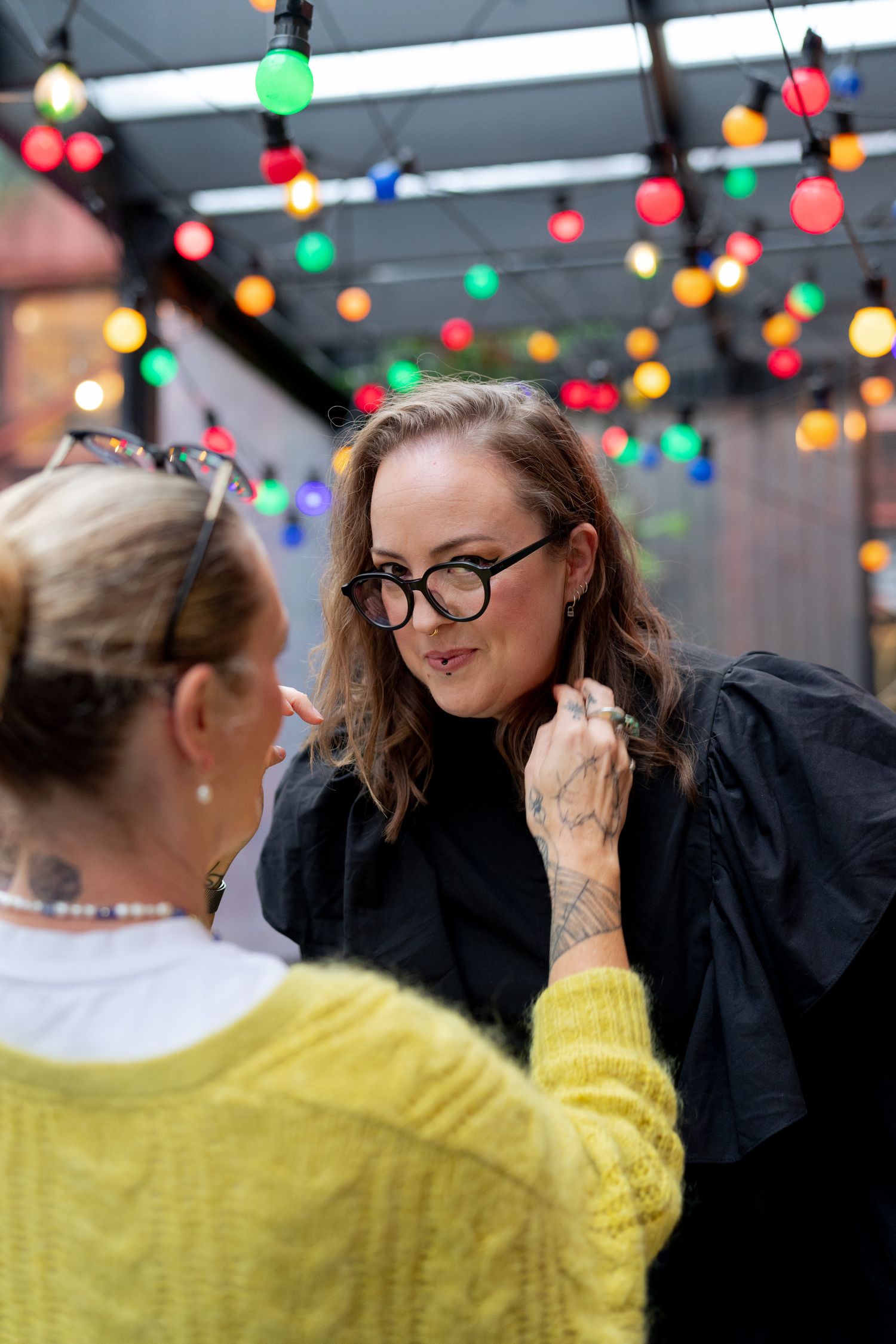 A behind the scenes picture of Emma having her hair adjusted by the makeup artist. They grin to the camera.