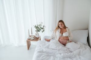 Zwangerschapsfoto blote buik lingerie in bed daglicht studio M te Moerbeke. Melissa Stuer Moederschapsfotograaf  fotograaf