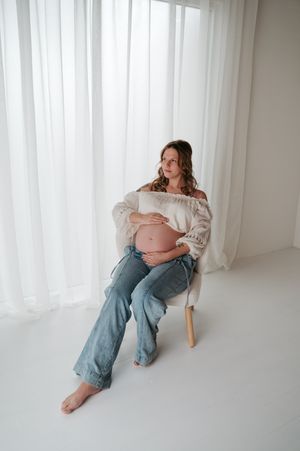Zwangerschapsfotoshoot blote buik in daglicht studio M te Moerbeke. Melissa Stuer Moederschapsfotograaf  fotograaf neutraal jeans wit