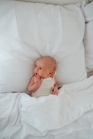 Newbornfotoshoot in daglicht studio M te Moerbeke. Melissa Stuer Moederschapsfotograaf  fotograaf. Pasgeboren baby in bed