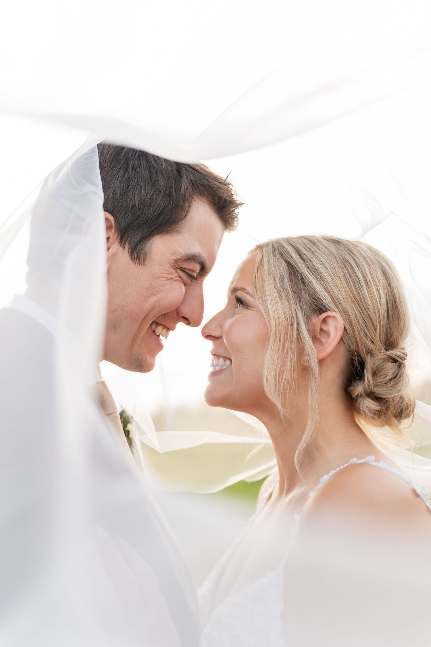 A romantic wedding couple shares tender moments under flowing white fabric in a series of intimate portraits.