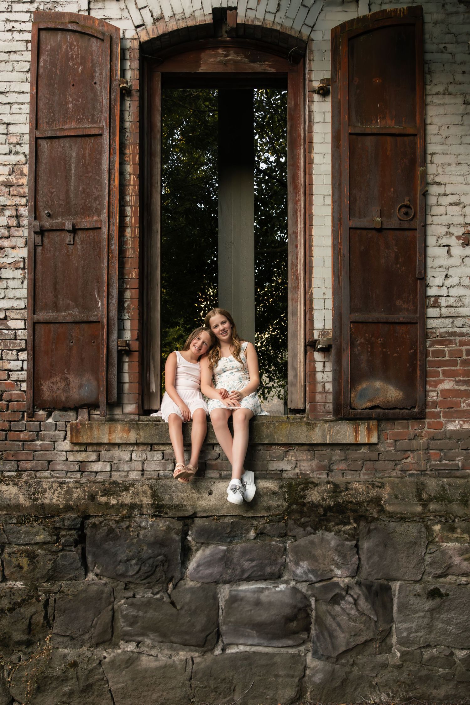 A series of artistic shots showing someone sitting in vintage window frames of an old brick building.