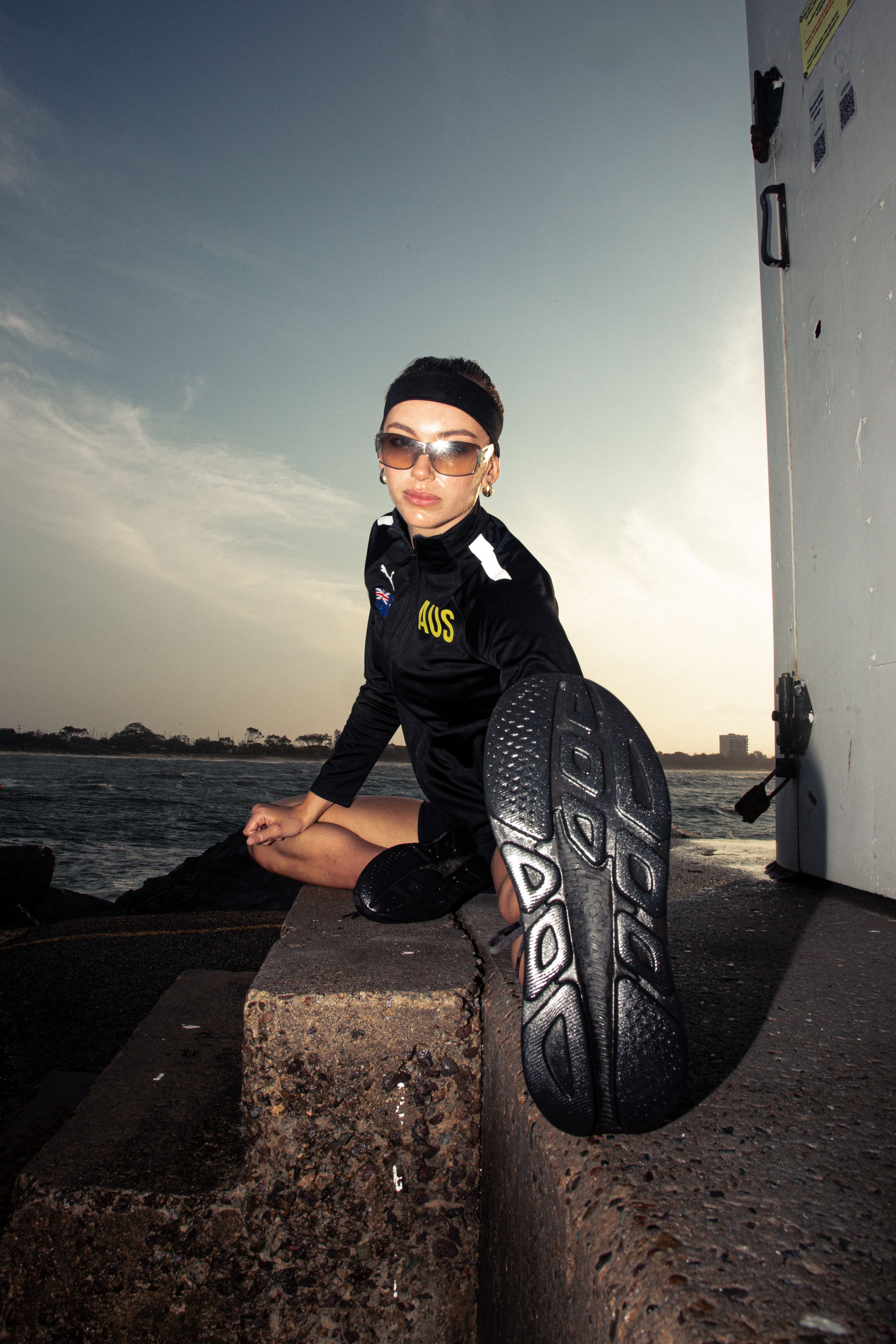 A series of sunset photos shows someone in dark clothing sitting on a concrete barrier by the ocean.