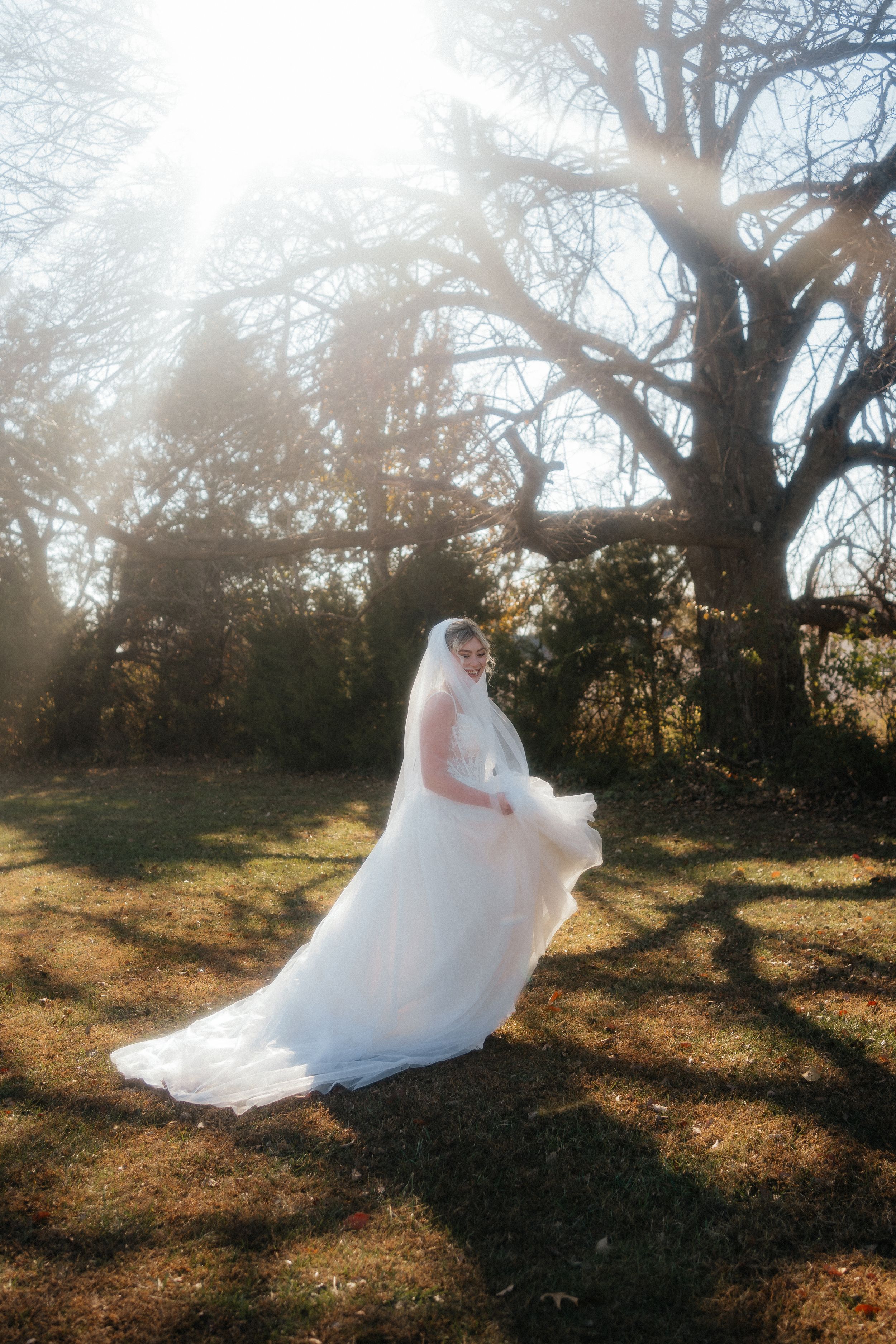 Ethereal wedding dress photos in silhouette against a sunset backdrop with bare winter trees and golden light.