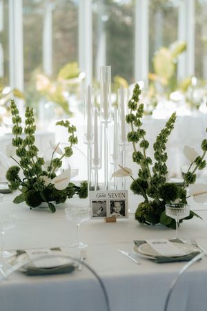 Elegant wedding table setting with white floral centerpieces, crystal glasses, and modern place settings in natural light.