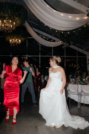 Wedding reception celebration in a tent venue with draped fabric, string lights and chandeliers creating romantic ambiance.