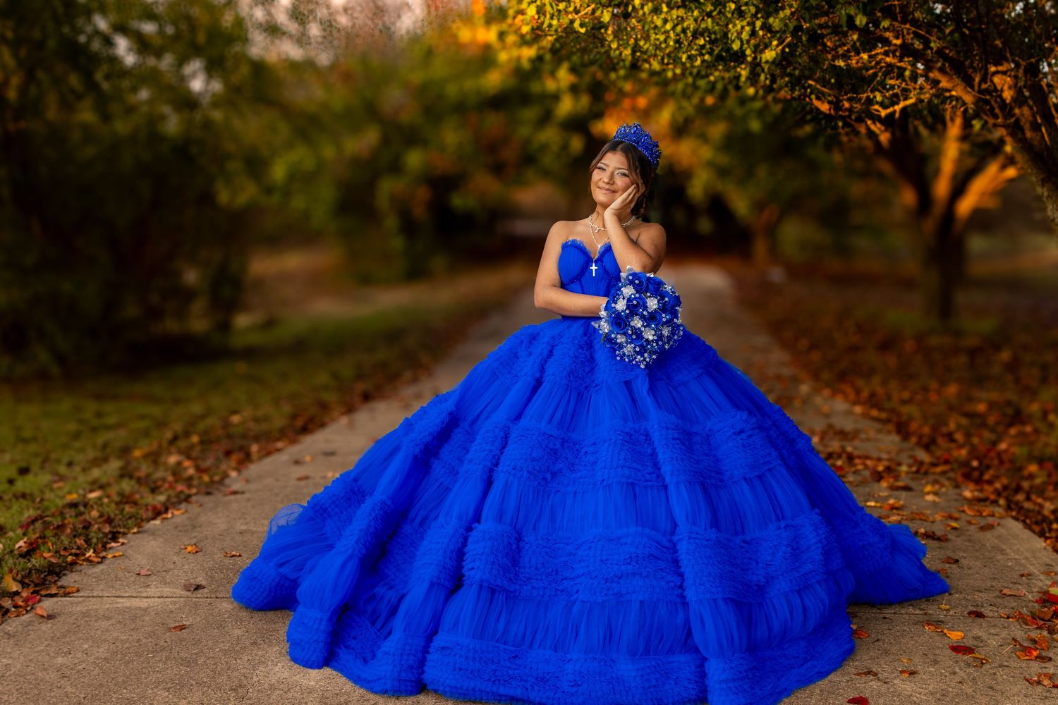 Quinceanera in flowing red gown posing against stone wall architecture.