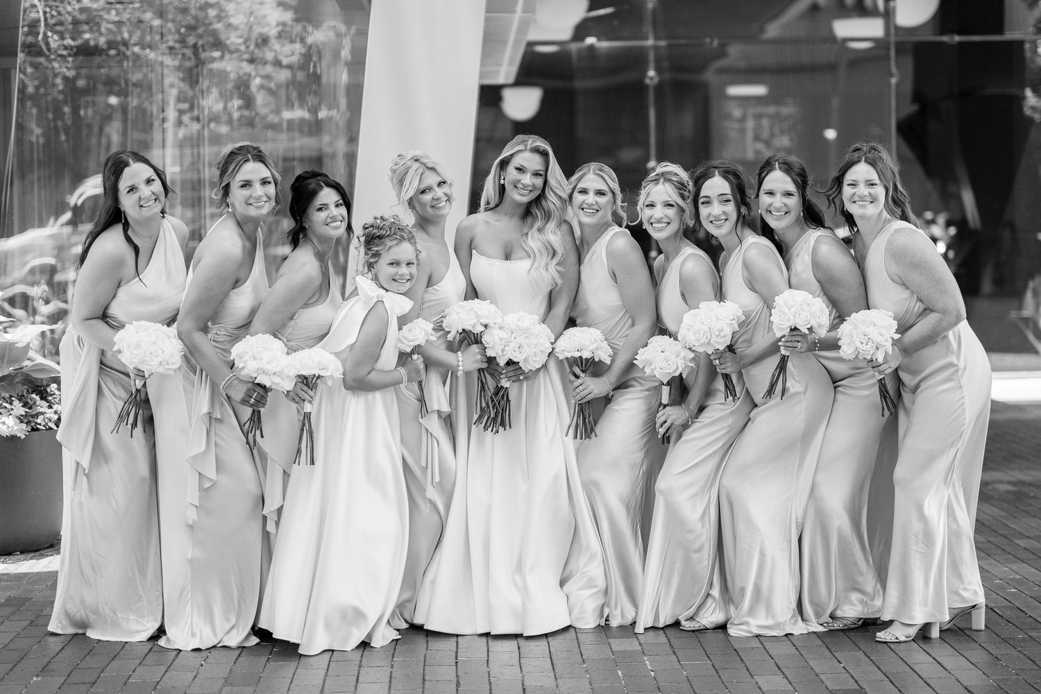 A series of four black and white photos showing bridesmaids in matching white dresses posing together at a wedding.