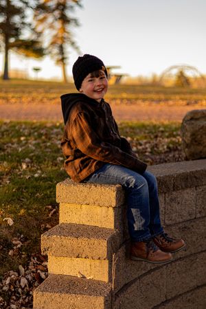 Child laughing while sitting on concrete steps during golden hour.