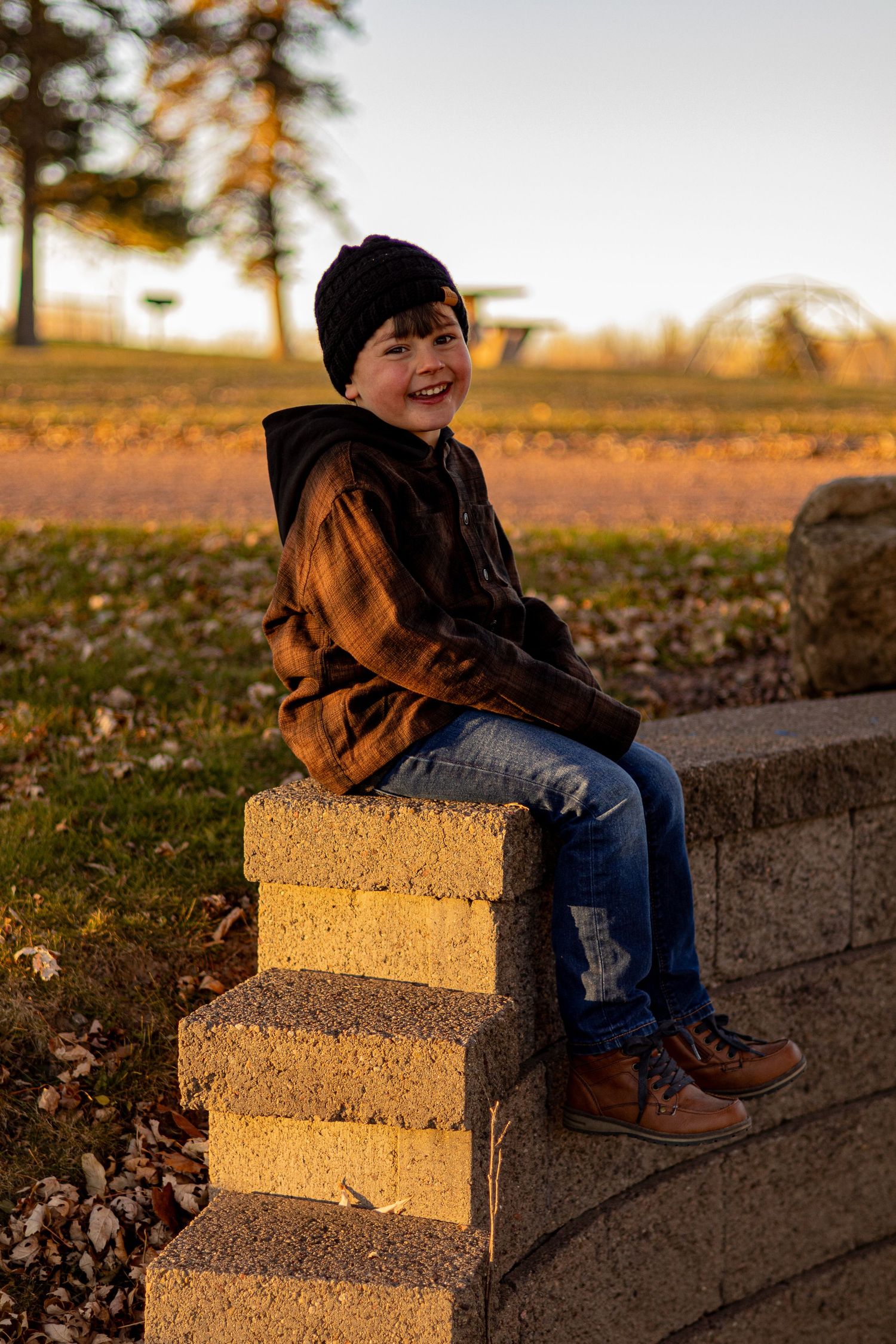 Child laughing while sitting on concrete steps during golden hour.